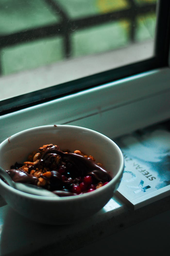 our-story Delicious breakfast bowl featuring nuts and berries beside a window sill.