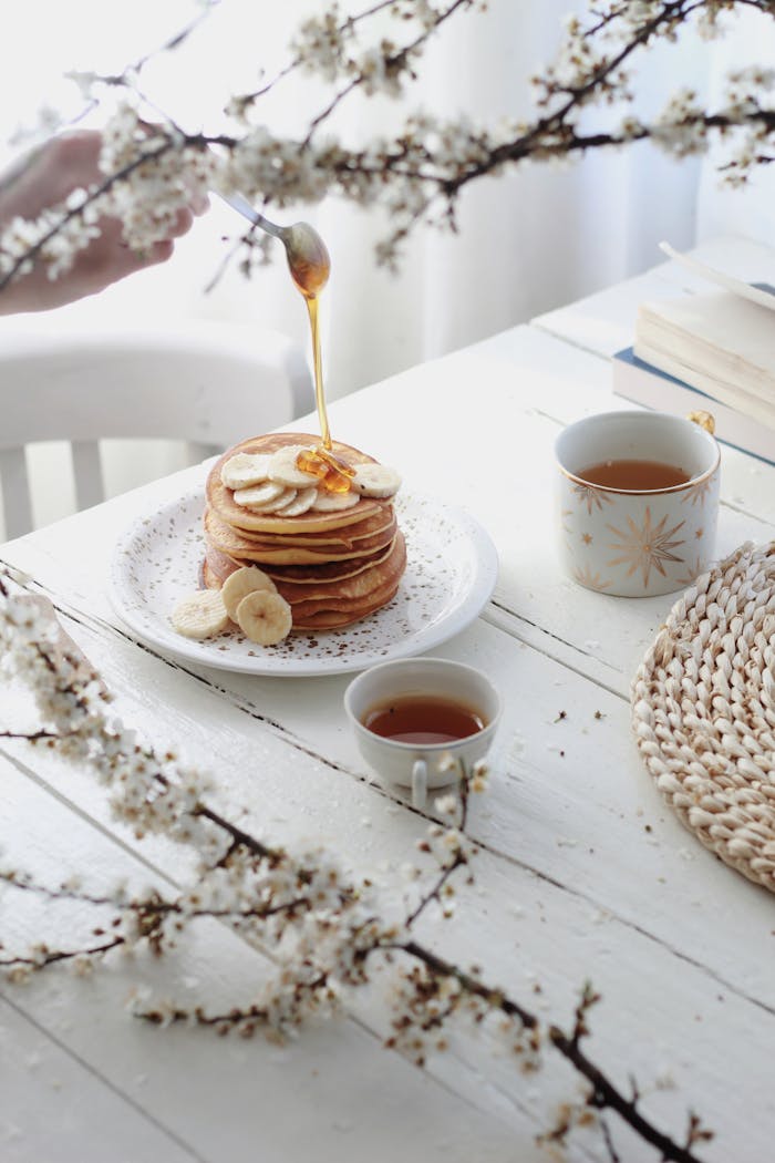 Crafting Captivating Headlines: Your awesome post title goes here High angle of unrecognizable person adding caramel topping on tasty pancakes with banana slices served on table with cups of tea in morning